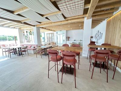 Helles Restaurant mit Holzmöbeln, bequemen Sitzgelegenheiten und modernen Dekorelementen.