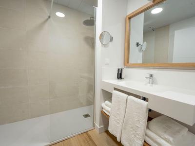 Modernes Badezimmer mit ebenerdiger Dusche und großem Spiegel.