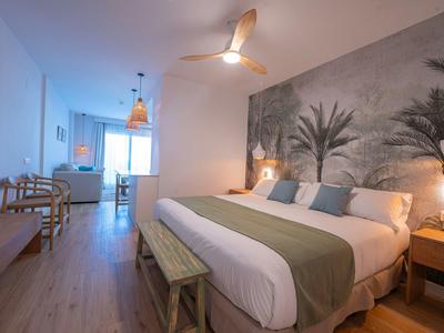 Modernes Hotelzimmer mit großem Bett, Palme-Wandbild und Holzboden.