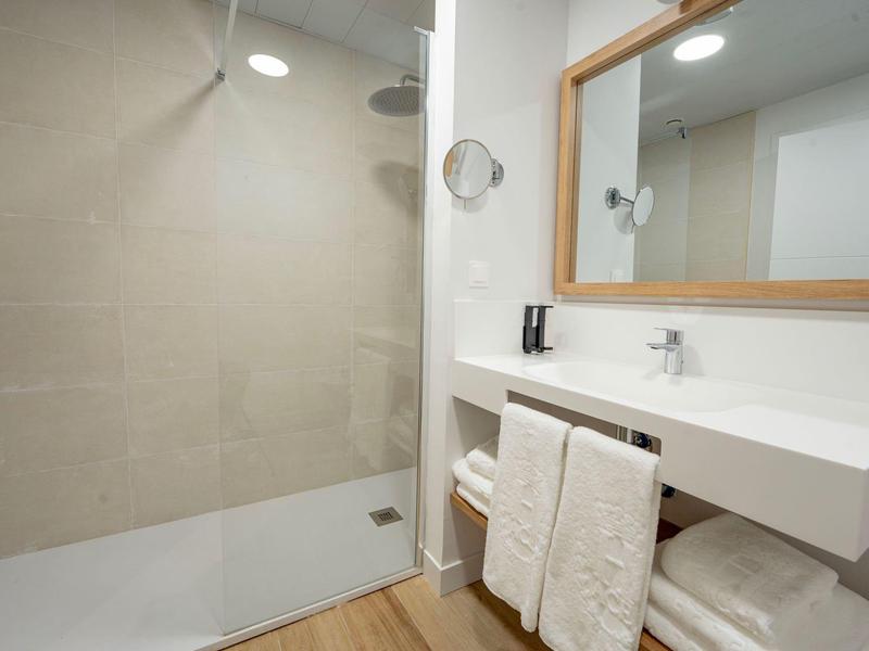 Modernes Badezimmer mit ebenerdiger Dusche und großem Spiegel.