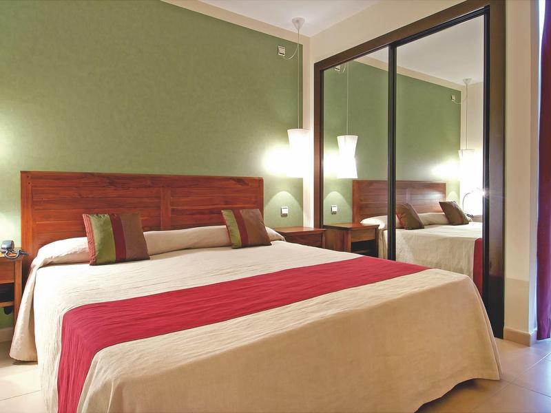 Pohodlný dvoulůžkový pokoj s velkou postelí, nočními stolky a skříní se zrcadlem.