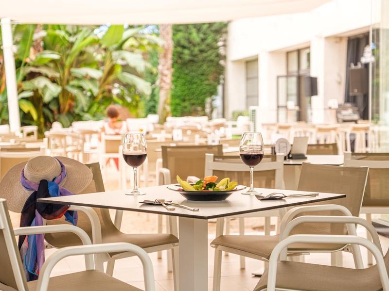 Stůl prostřený s vínem a jídlem na hotelové terase za denního světla.