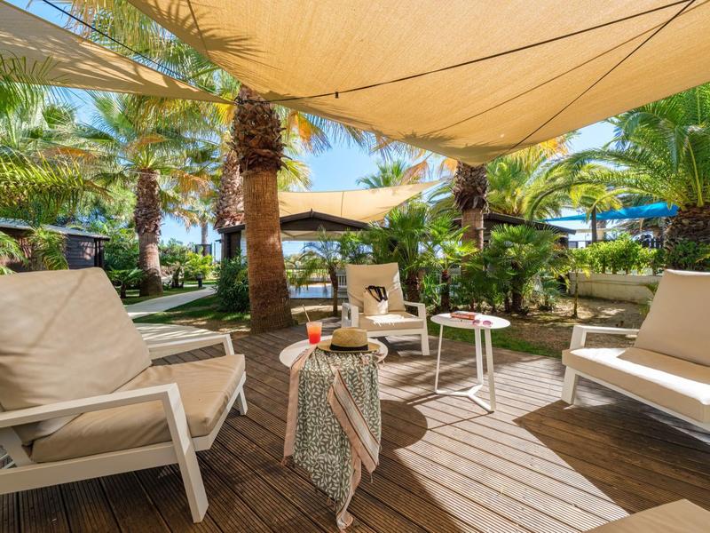 Rincón acogedor con sombra y palmeras en un jardín tropical de un hotel.