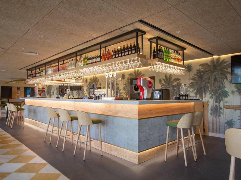 Bar moderno con taburetes altos y una iluminación cálida en un ambiente acogedor de hotel.