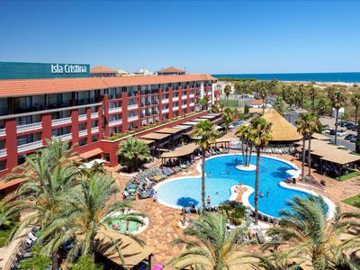Hotel con piscina, palme e vista mare sotto un cielo limpido.