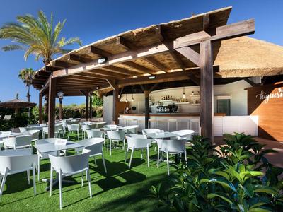 Area esterna con sedie bianche e tetto in legno sotto un cielo limpido in un hotel.