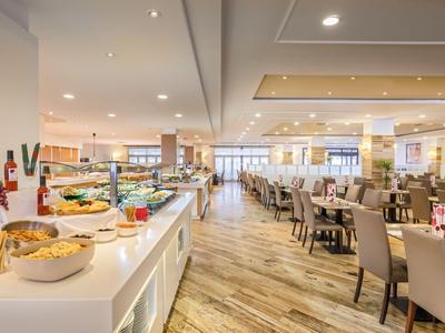 Ristorante d'hotel luminoso con buffet per la colazione, sedie e pavimento in legno.