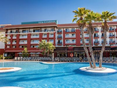 Hotel moderno con grande piscina all'aperto e palme sotto un cielo azzurro.