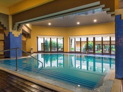 Piscina interior con grandes ventanas y azulejos azules en un hotel.