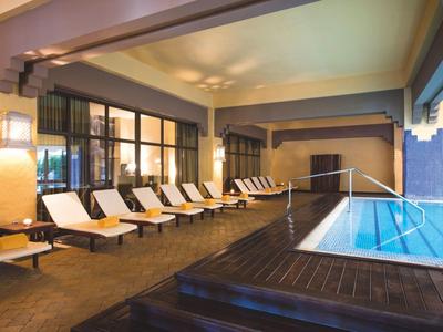 Área interior con piscina climatizada y tumbonas en un hotel moderno.