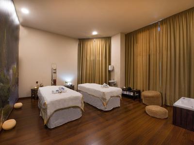 Sala de spa acogedora con dos camillas de masaje, suelo de madera cálido y luz tenue.