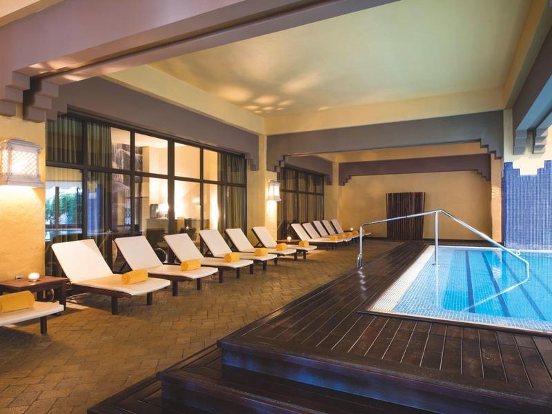 Área interior con piscina climatizada y tumbonas en un hotel moderno.