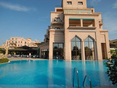 Grand bâtiment d'hôtel avec une impressionnante piscine sous un ciel dégagé.