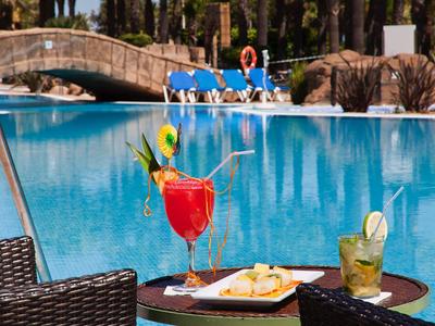 Cocktails et snacks sur une table à côté d'une piscine avec un pont en arrière-plan.