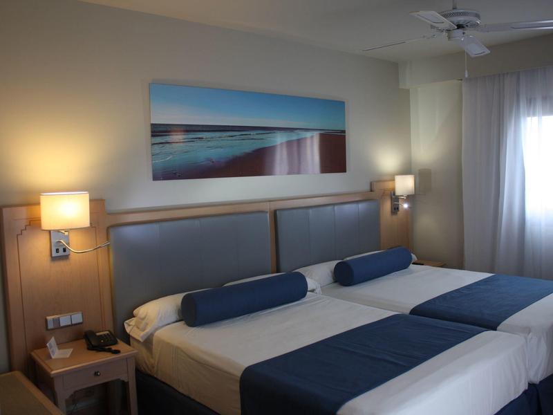 Chambre d'hôtel moderne avec deux lits et éclairage indirect.