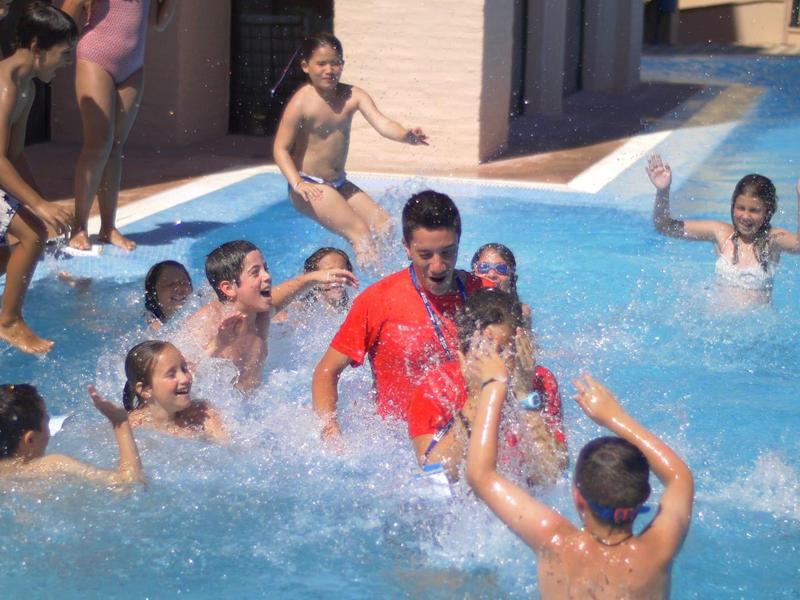 Des enfants jouent et éclaboussent joyeusement dans une piscine peu profonde par une journée ensoleillée.