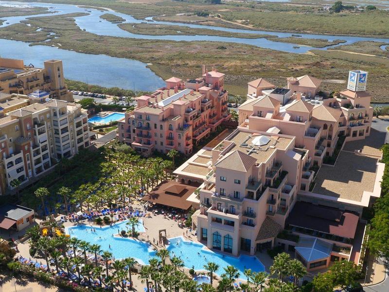 Hôtel de luxe avec grande piscine à côté d'une rivière et zone humide dans un cadre verdoyant.