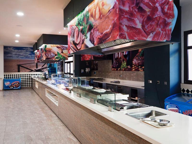 Cafétéria moderne avec un long comptoir en libre-service et des motifs colorés de viande au plafond.