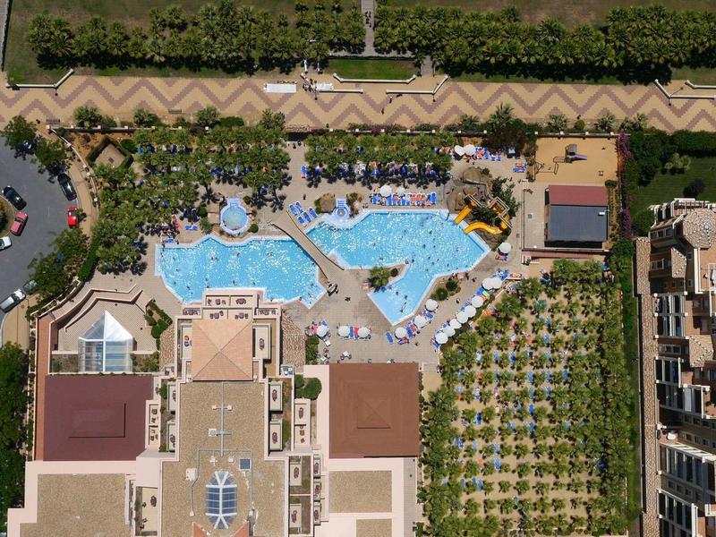 Vue aérienne d'un hôtel avec grande piscine, espaces verts et parking