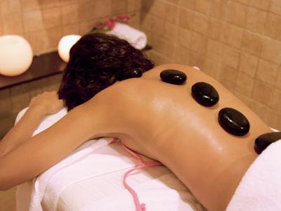 Innenraum mit kleinem Wellnesspool, künstlichem Felsen, Kerzen und einfacher Holzbank.