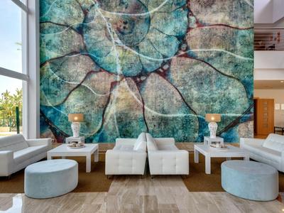 Großes Wohnzimmer mit heller Einrichtung und auffälliger, großer Wandgestaltung in Blau- und Grüntönen.