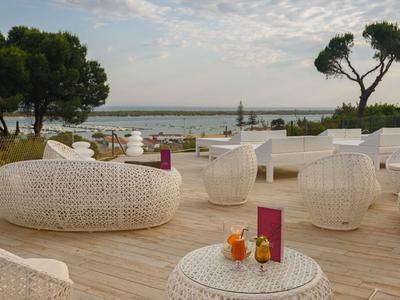 Terrace with white, modern seating and a view of the beach and sea under a cloudy sky.