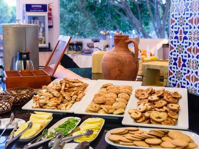 Vielfältige Kekse und Keksscheiben auf weißen Tellern, mit Besteck und Dekoration im Hintergrund.