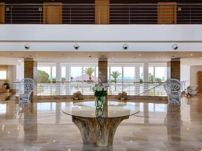 Großer heller Raum mit Marmorboden, Holzsäulen und mittigem Marmorquadrat mit Blumenvase.