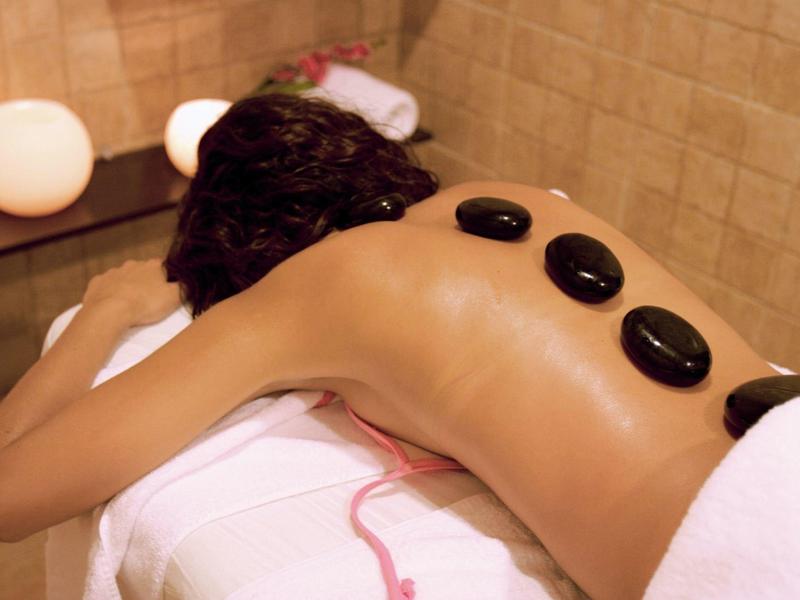 Innenraum mit kleinem Wellnesspool, künstlichem Felsen, Kerzen und einfacher Holzbank.