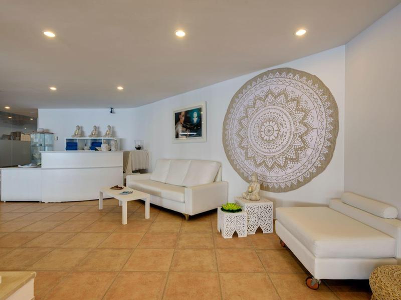 Moderner Warteraum mit weißen Möbeln, rundem Wandbild und terrakottafarbenem Fliesenboden.