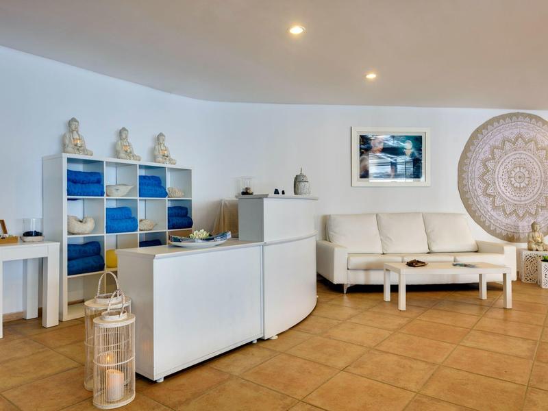 Modernes Wohnzimmer mit weißem Sofa, blau-weißem Regal, rundem Wandbild und terrakottafarbenem Boden.