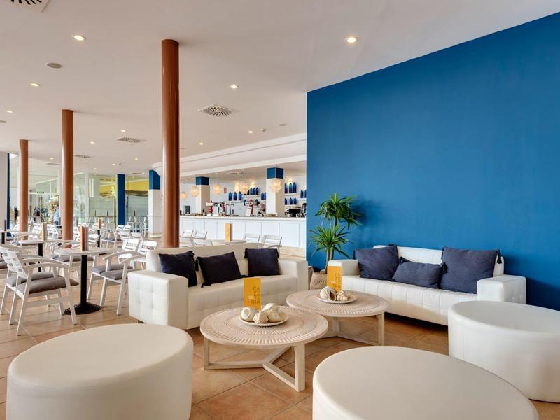 Moderner Gastraum mit blauer Akzentwand, weißen Möbeln und Holzböden, hell und einladend.