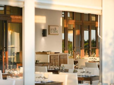 Ristorante luminoso e accogliente con tovaglie bianche e mobili in legno al tramonto.