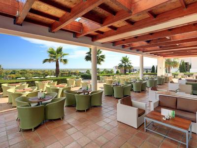 Terrazza aperta dell'hotel con poltrone verdi vista mare e palme.