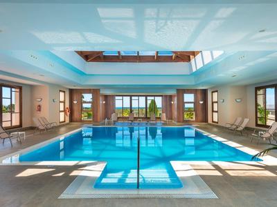 Piscina coperta luminosa con grande vasca rettangolare e finestre panoramiche.