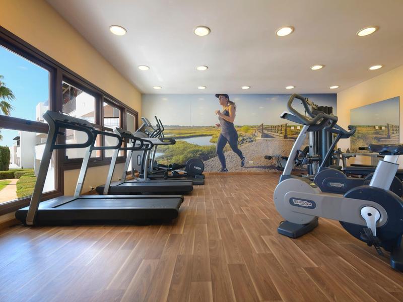 Palestra moderna con tapis roulant, cyclette e finestre panoramiche.