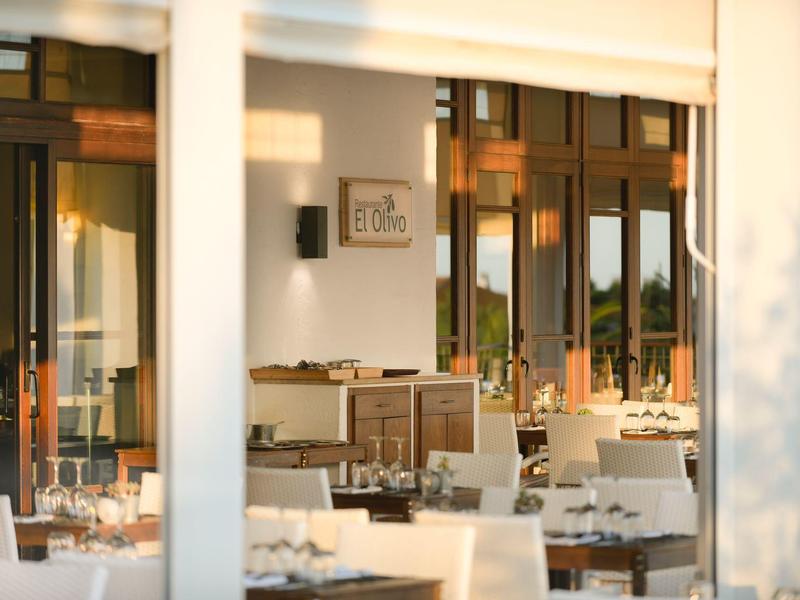 Ristorante luminoso e accogliente con tovaglie bianche e mobili in legno al tramonto.