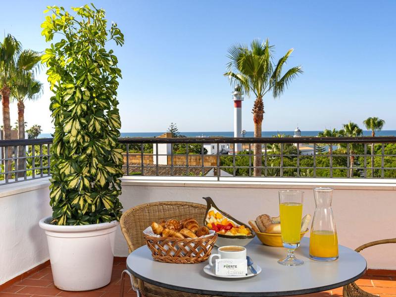 Balcone con tavolo per la colazione, piante e vista sul mare sotto un cielo limpido