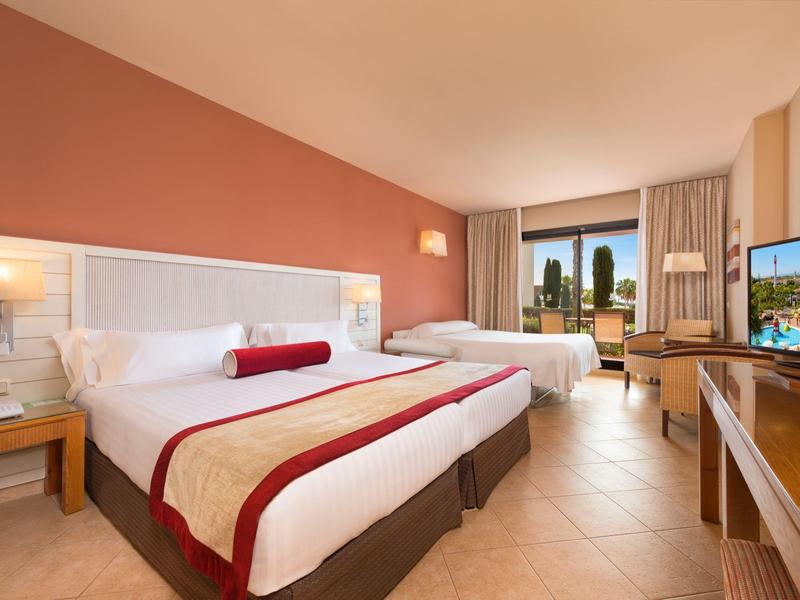 Camera d'hotel luminosa con due letti grandi, TV e vista sulla città