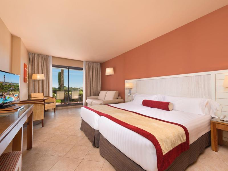 Camera d'hotel luminosa con letto king-size, divano, scrivania e finestra con vista.