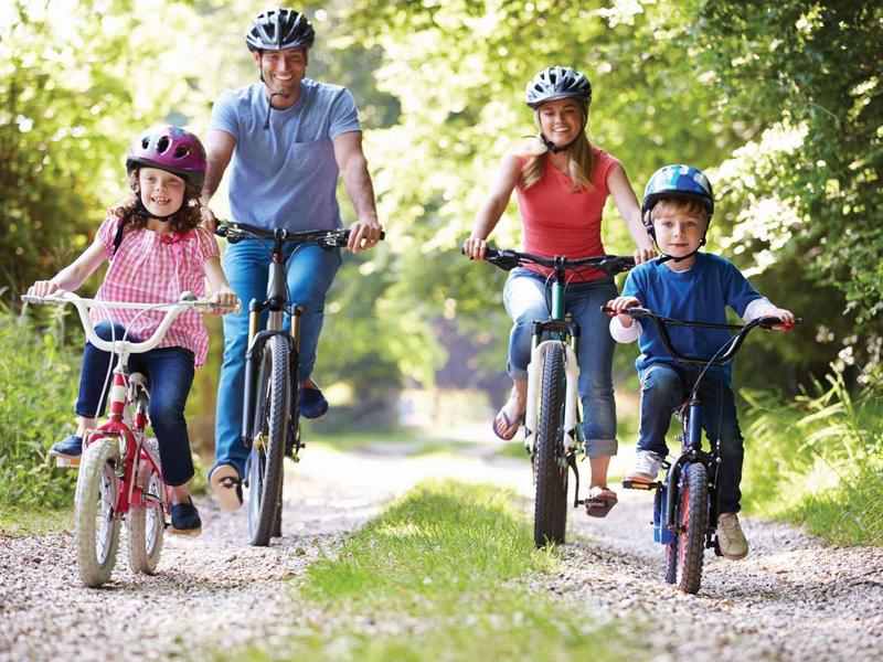 Famiglia con due bambini che pedalano su un sentiero boscoso.