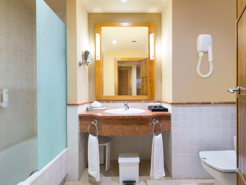 Bagno luminoso con lavabo, specchio, asciugamani, asciugacapelli e WC.