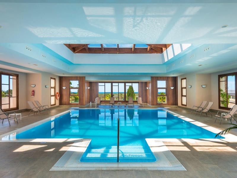 Piscina coperta luminosa con grande vasca rettangolare e finestre panoramiche.