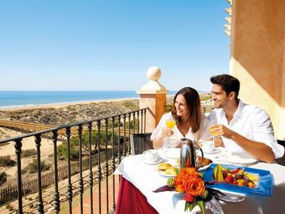 Stel genietend van ontbijt op balkon met uitzicht op oceaan en zonnig weer