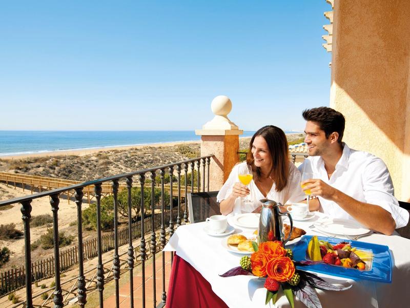 Stel genietend van ontbijt op balkon met uitzicht op oceaan en zonnig weer