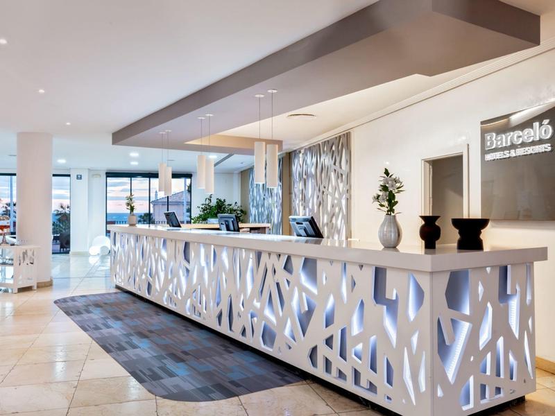 Moderne hotelreceptie met decoratieve balie, potplanten en heldere binnenverlichting.