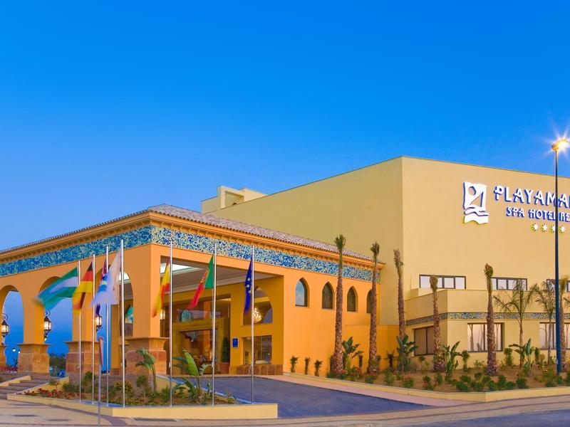 Modernes Hotelgebäude mit großen Fenstern, bunter Fassade und blauem Himmel im Hintergrund.