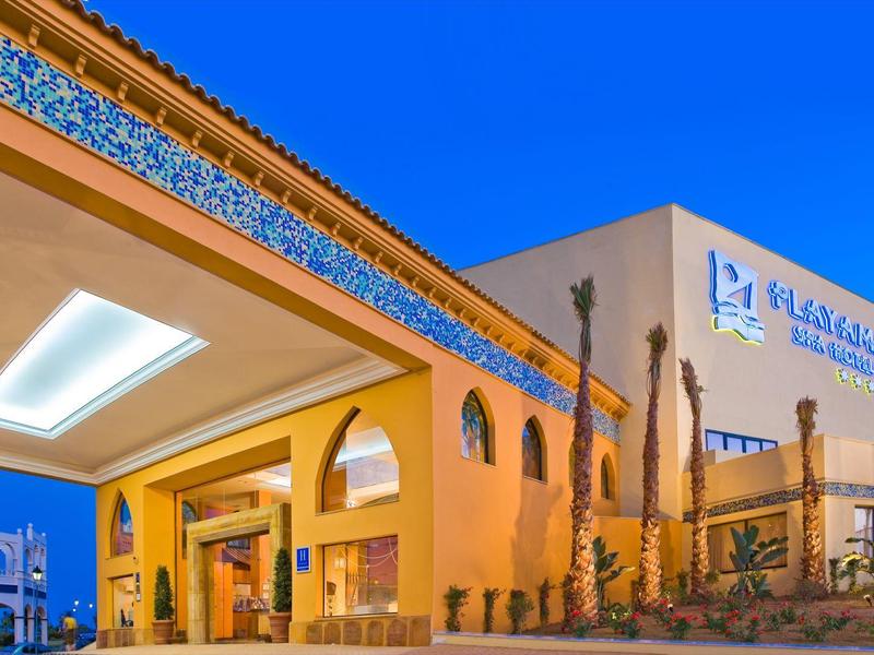 Hotelgebäude mit gelber Fassade, arabischen Stilelementen und blauem Himmel im Hintergrund.