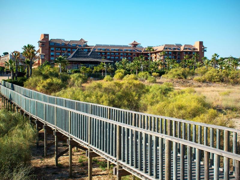 Hell eingerichtetes Schlafzimmer mit Doppelbett, Schrägdachfenstern und roten Fliesenboden.