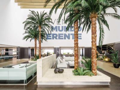Lobby di hotel moderna con alte palme, aree salotto accoglienti e design luminoso e aperto.